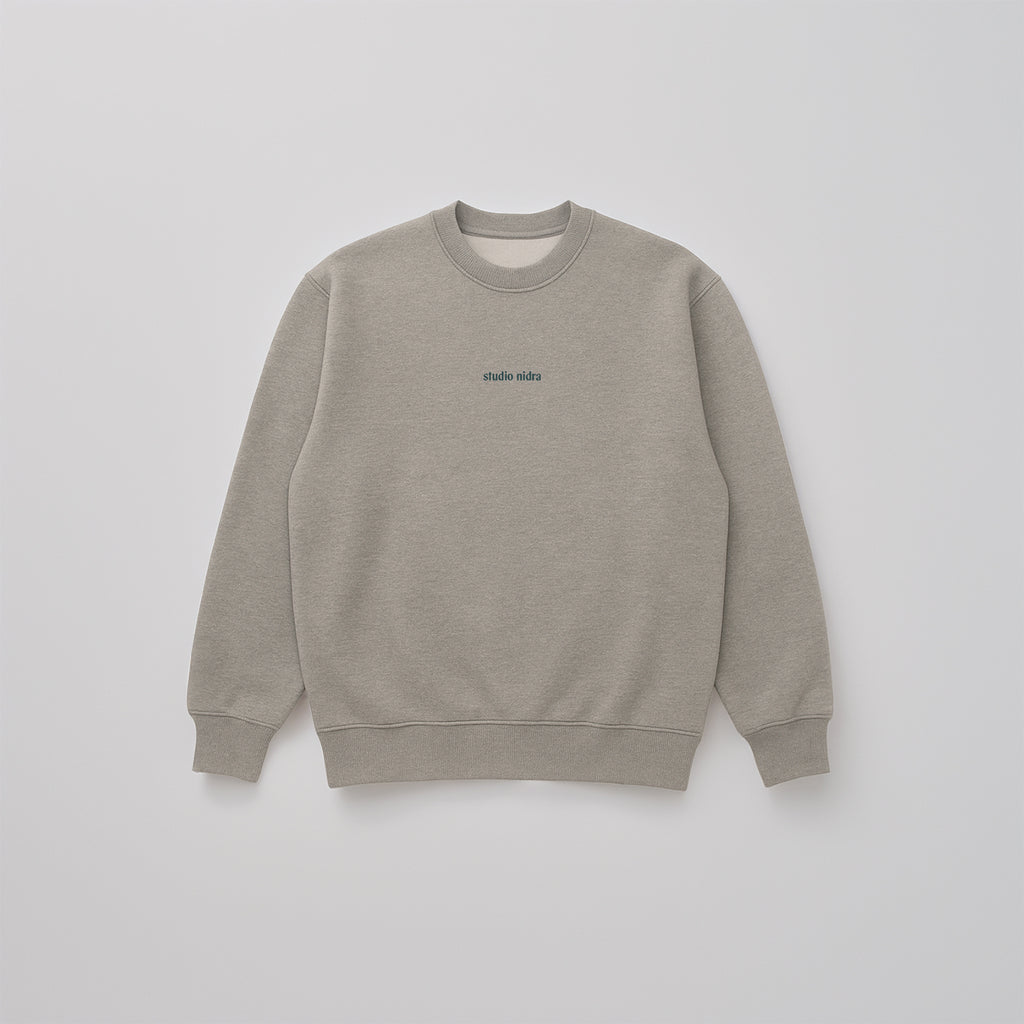 Flatlay image of Gray marle organic cotton sweatshirt in limited edition "Grey Matter" with a Studio Nidra logo embroidery on a light gray background