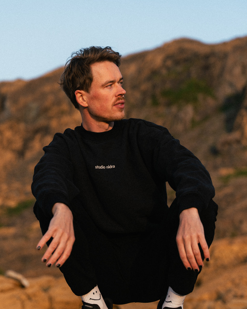 The Crew Sweatshirt black - lifestyle shot of a man wearing Studio Nidra sustainable luxury activewear.