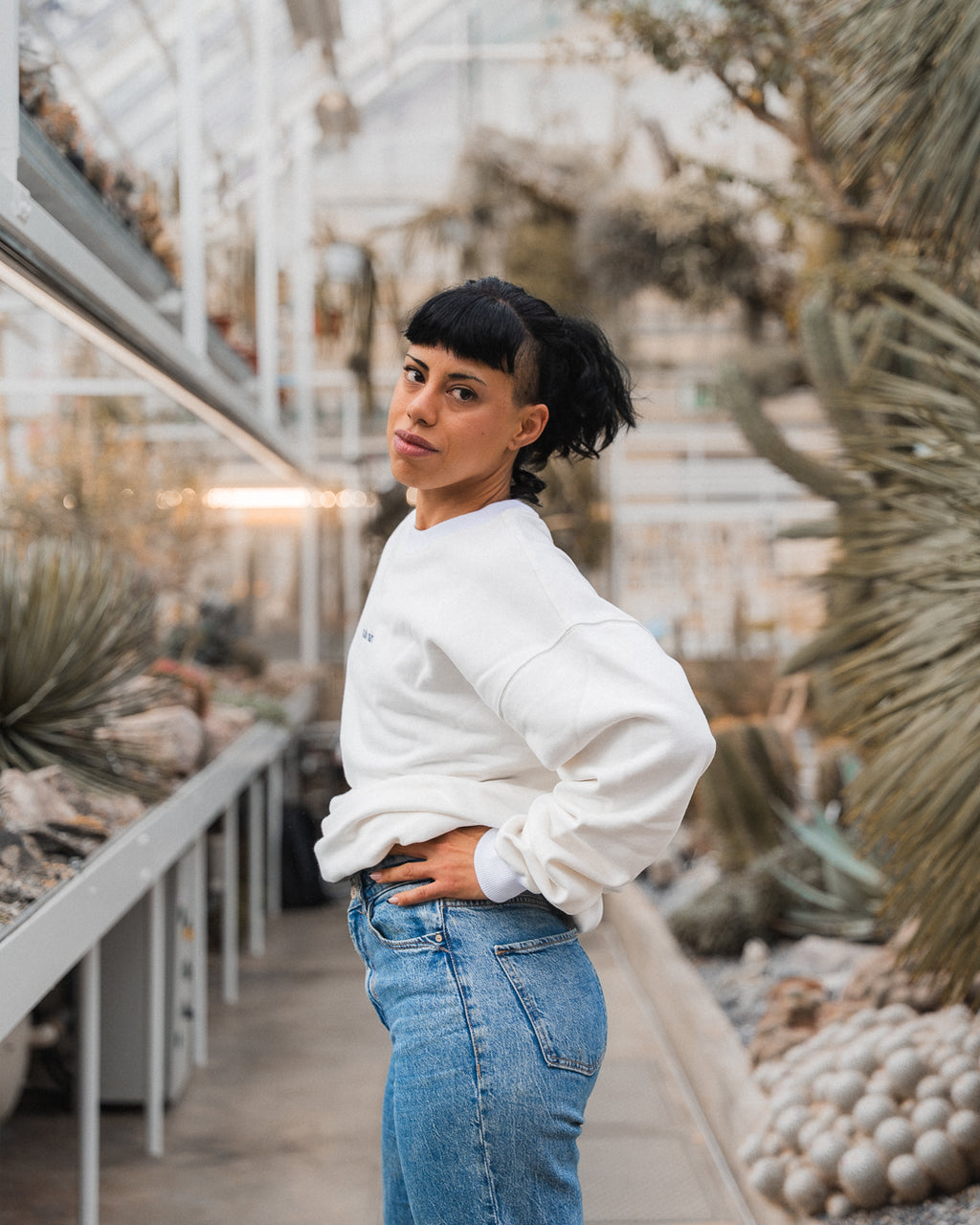 Woman wearing The Crew white sweatshirt and blue jeans - relaxed fit sustainable luxury
